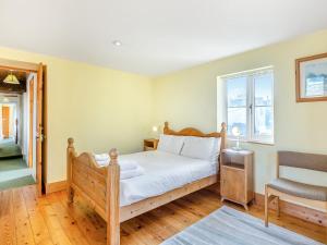 a bedroom with a wooden bed and a window at Prosperous Villa in Puncknowle +16 photos