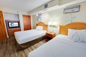 a hotel room with two beds and a flat screen tv at New Beachfront, Condo Simply Amazing Pools & Views in Myrtle Beach