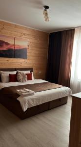 a bedroom with a large bed with wooden walls at MiS Family house з чаном та сауною in Kosiv