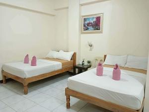 two beds in a room with pink containers on them at Constrell Pension House in Tagbilaran City