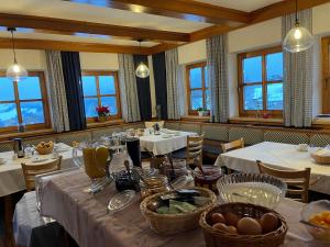 a dining room with white tables and chairs and windows at Pension Patz in Schladming