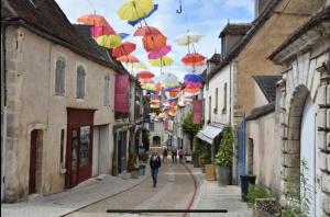 a man walking down a street with umbrellas in the air at Le Petit Sancerrois in Sancerre