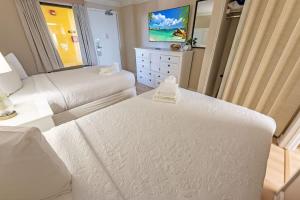 a white bedroom with two beds and a television at Direct Ocean Front, The Pavilion, Pools, Boardwalk in Myrtle Beach