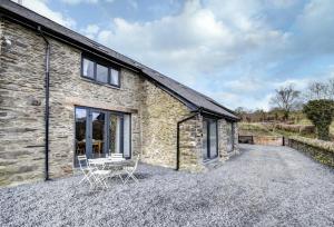 a stone cottage with two chairs on a gravel driveway at 5 Bed in Machynlleth oc-bow30 in Darowen