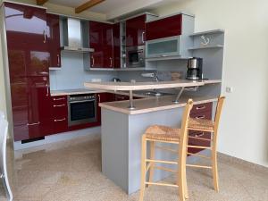 a kitchen with red cabinets and a counter with two chairs at Cliner Blick in Wittmund
