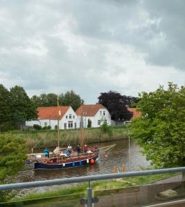 a boat on a river with houses in the background at Cliner Blick in Wittmund +9 photos