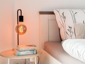 a table with books and a lamp next to a bed at Ferienwohnung Seeschlösschen am Dümmer See in Lembruch