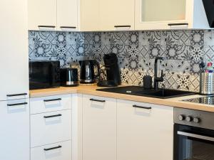 a kitchen with white cabinets and a black and white wallpaper at Ferienwohnung Seeschlösschen am Dümmer See in Lembruch +14 photos