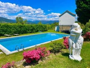a statue of a woman next to a swimming pool at Solar Alegria Lodge in Oliveira de Frades
