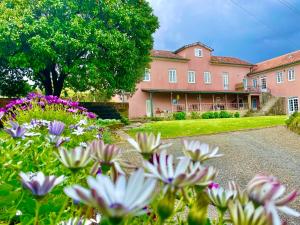 a large pink house with flowers in the yard at Solar Alegria Lodge in Oliveira de Frades