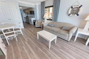 a living room with a couch and a table at 1BR Direct Oceanfront Views at Palms - Nice Pools! in Myrtle Beach
