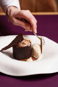 a person eating a piece of chocolate cake on a plate at Les Jardins d'Anaïs in Luxembourg