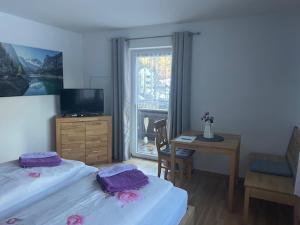 a bedroom with two beds and a desk and a window at Gästehaus Lehnerer Grainau in Grainau