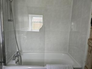 a bathroom with a bath tub with a window at The White House Hotel in Williton