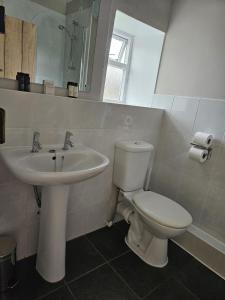 a bathroom with a white toilet and a sink at The White House Hotel in Williton