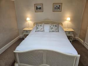 a white bed in a room with two lamps at The White House Hotel in Williton