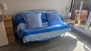 a bed with blue sheets and pillows in a room at Col de L'Arzelier in Château-Bernard