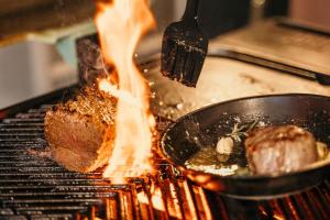 a steak being cooked on a grill with flames at Marrian George Hotel in Koringberg