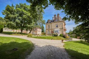 an old house with a tree and a driveway at Les Villas d'Arromanches, Teritoria in Arromanches-les-Bains