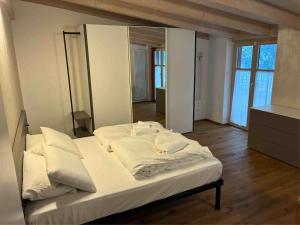 a bedroom with a bed with white sheets and pillows at Respiro di lago in Molveno +3 photos