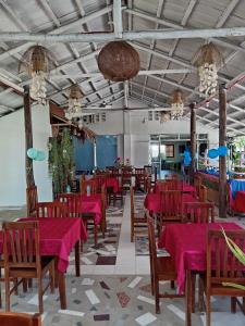 a dining room with red tables and chairs and chandeliers at La Bottega Pension House in Roxas