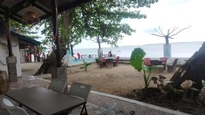 a table and chairs on a beach with the ocean at La Bottega Pension House in Roxas +14 photos