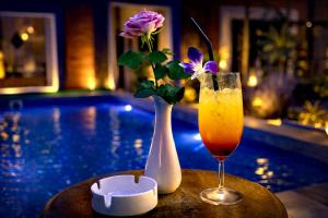 a table with a vase of flowers and a drink at Angkor Rithy Residence in Siem Reap