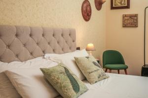a bedroom with a white bed with a green chair at Villa Monica in Le Bolle