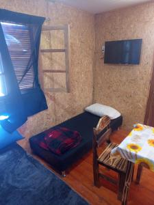 a room with a bed and a tv and a chair at El Refugio in Santa Vitória do Palmar