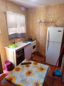 a kitchen with a refrigerator and a table with flowers on it at El Refugio in Santa Vitória do Palmar