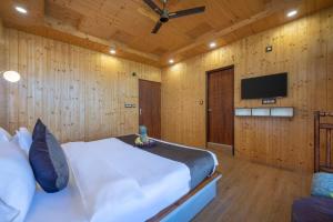 a bedroom with a bed and a flat screen tv at Whispering Woods Homestay Kasauli !! in Kasauli