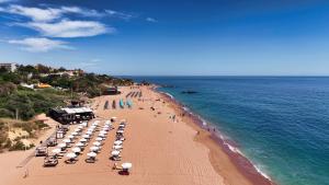 a beach with umbrellas and people on the beach at Hotel Apartamento Paraiso De Albufeira in Albufeira