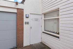 a white house with two garage doors and a window at Zaras Studio Hermes in Zandvoort +27 photos