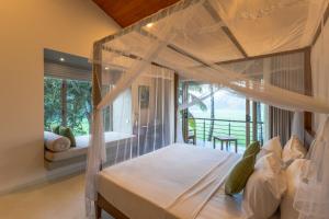 a bedroom with a canopy bed and a balcony at ONA Garden Villa in Galle