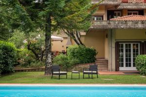 two chairs and a pool in front of a house at Villa Monica in Le Bolle
