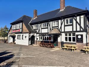 a black and white building with benches in a parking lot at The Wrey Arms in Barnstaple