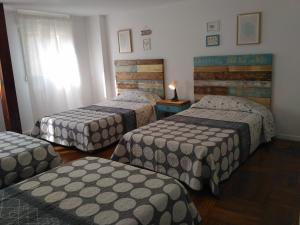 a hotel room with three beds and a window at Casona MilaWen in Potes