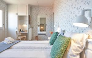 a bedroom with a large white bed with green pillows at Klippen Hotel - Therns in Gudhjem