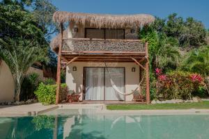 a house with a hammock next to a swimming pool at Villas AHAL, in Chemuyil
