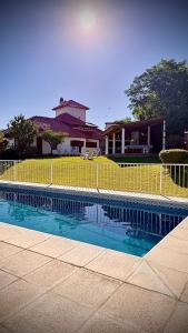 a swimming pool with a yellow fence in front of a house at Cabanas Las Pencas, HOSTERIA in Mina Clavero