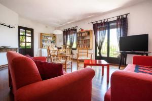 a living room with red chairs and a flat screen tv at Apartament amb vistes al castell - Cal Martí in Montsonis