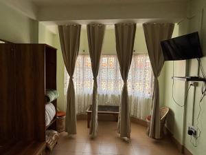 a room with a window with curtains and a television at The Parijat Inn in Mirik