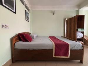 a bedroom with a wooden bed with red pillows on it at The Parijat Inn in Mirik