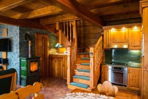 a log cabin kitchen with stairs and a stove at Chalupa u Macochy in Blansko