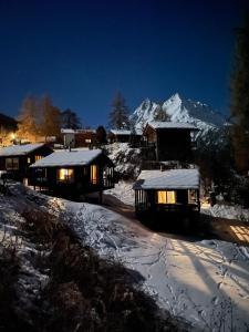 a group of cabins in the snow at night at minipockethouse in Evolène +4 photos
