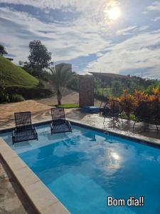 a swimming pool with two chairs at Rancho dos Ipês Corumbá in Alexânia