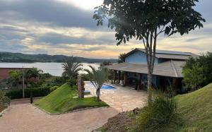 a house with a garden and a lake in the background at Rancho dos Ipês Corumbá in Alexânia