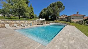a swimming pool in a yard with a stone wall at Château de la Chabroulie in Isle