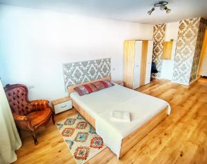 a bedroom with a large white bed and a chair at Studio Miruna in Piatra Neamţ