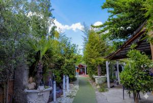 a path through a garden with trees and a building at Hôtel La Palmeraie in Toulouse